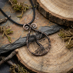 Copper tree of life pendant on a black cord with a natural wood background