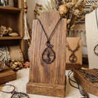 Jewelry display with a necklace on a wooden stand, surrounded by decorative items.