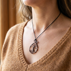Person wearing a necklace with a tree pendant, close-up on neck and chest.