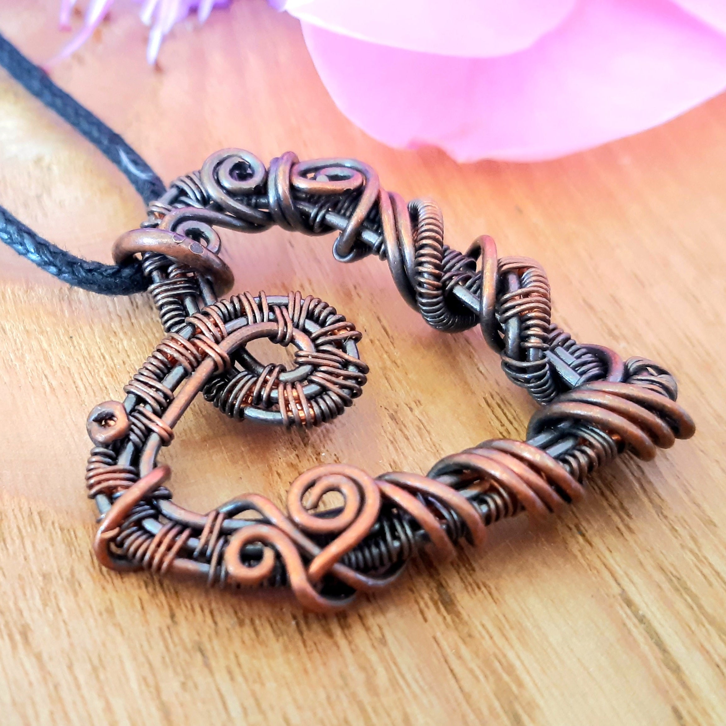 Copper wire-wrapped pendant on a wooden surface with a blurred background