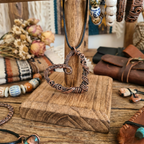 Copper heart-shaped necklace on a wooden stand with various jewelry items in the background.