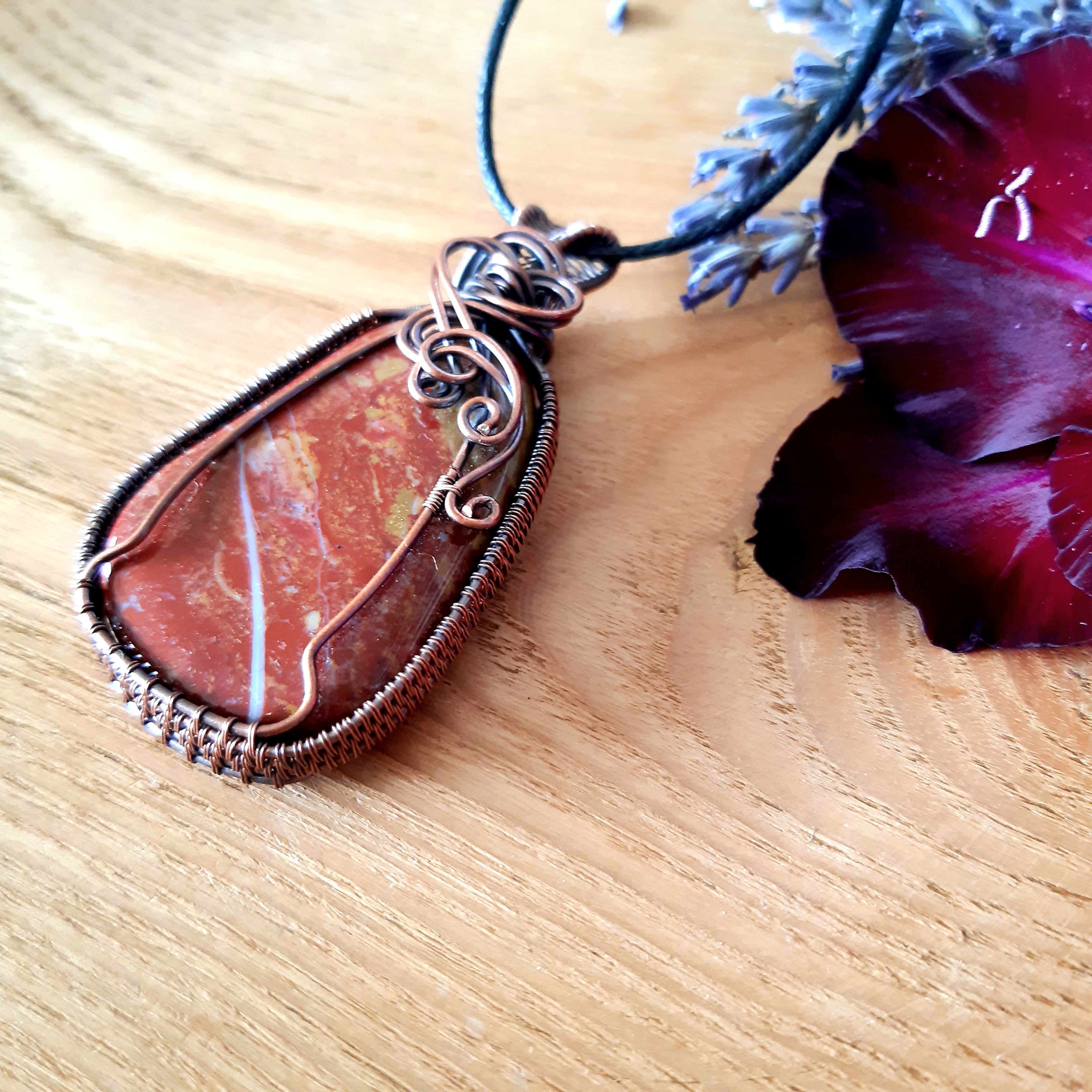 Jasper pendant necklace on a wooden surface with a purple flower