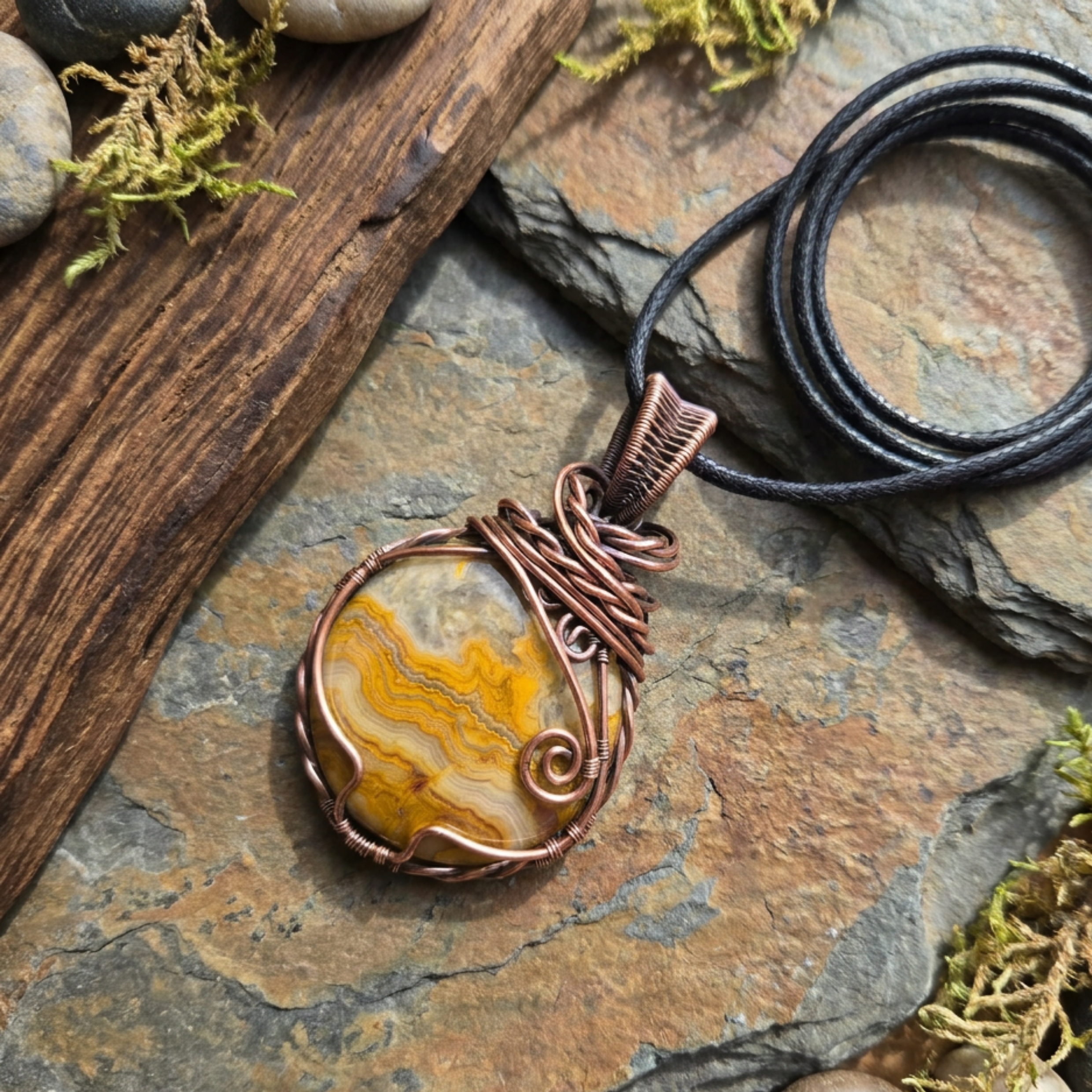 Copper-wrapped pendant with a stone-like center on a stone surface