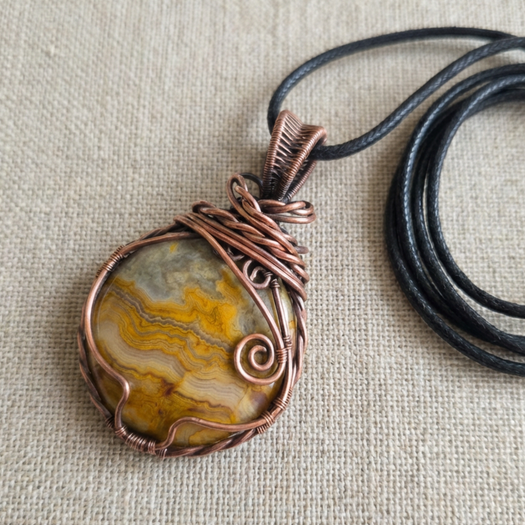 Necklace with a stone pendant wrapped in copper wire on a beige fabric background