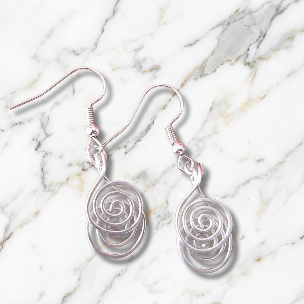 Silver spiral earrings on a marble surface