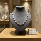 Handmade silver spiral necklace on a gray stand with a label in a jewelry store setting.