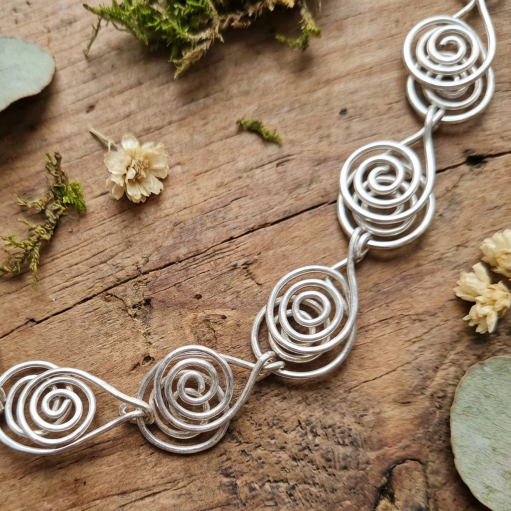 Detailed view of a Silver wire spiral necklace on a wooden surface with natural elements