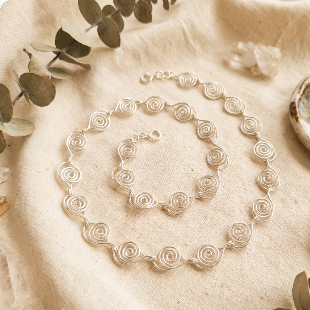 Silver necklace on a textured beige surface with green leaves