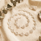Silver necklace on a textured beige surface with green leaves