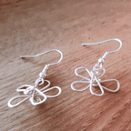 Pair of white wire butterfly earrings on a wooden surface