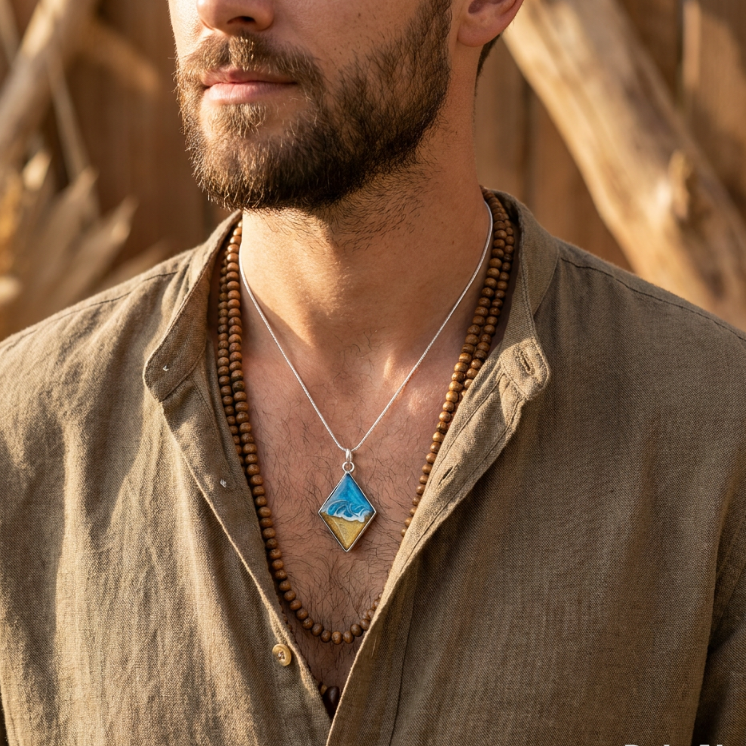 Man wearing a necklace with a blue pendant against a natural background