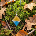 Necklace with a geometric pendant on a background of green moss and brown leaves