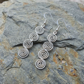 Silver spiral earrings on a stone surface