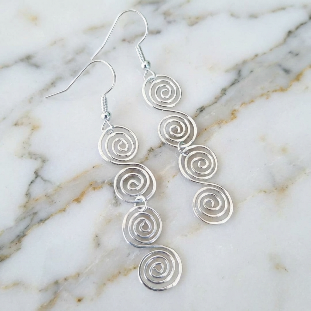 Silver spiral earrings on a marble surface