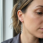 Close-up of a woman wearing silver spiral earrings with a neutral background