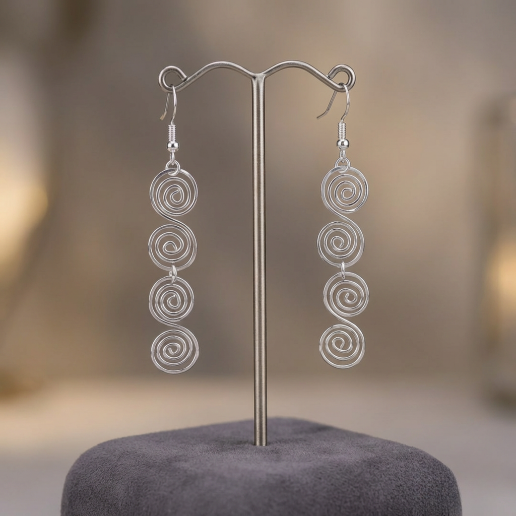 Silver spiral earrings on a stand with a blurred background