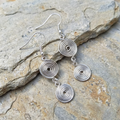 Silver spiral earrings on a stone surface