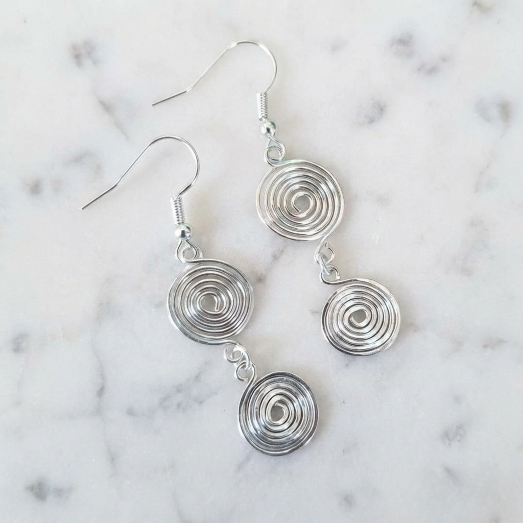 Silver spiral earrings on a marble background