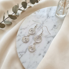 Silver spiral earrings on a marble surface with a soft background