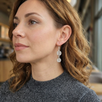 Close-up of a woman wearing silver spiral drop earrings with a blurred indoor background