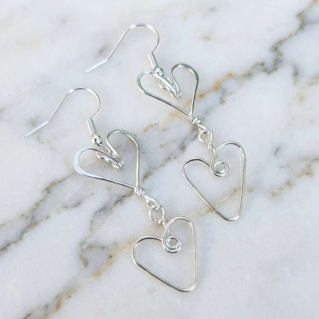 Silver heart-shaped earrings on a marble surface