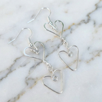 Silver heart-shaped earrings on a marble surface