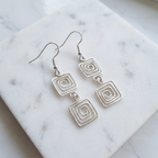 Silver square earrings on a marble surface