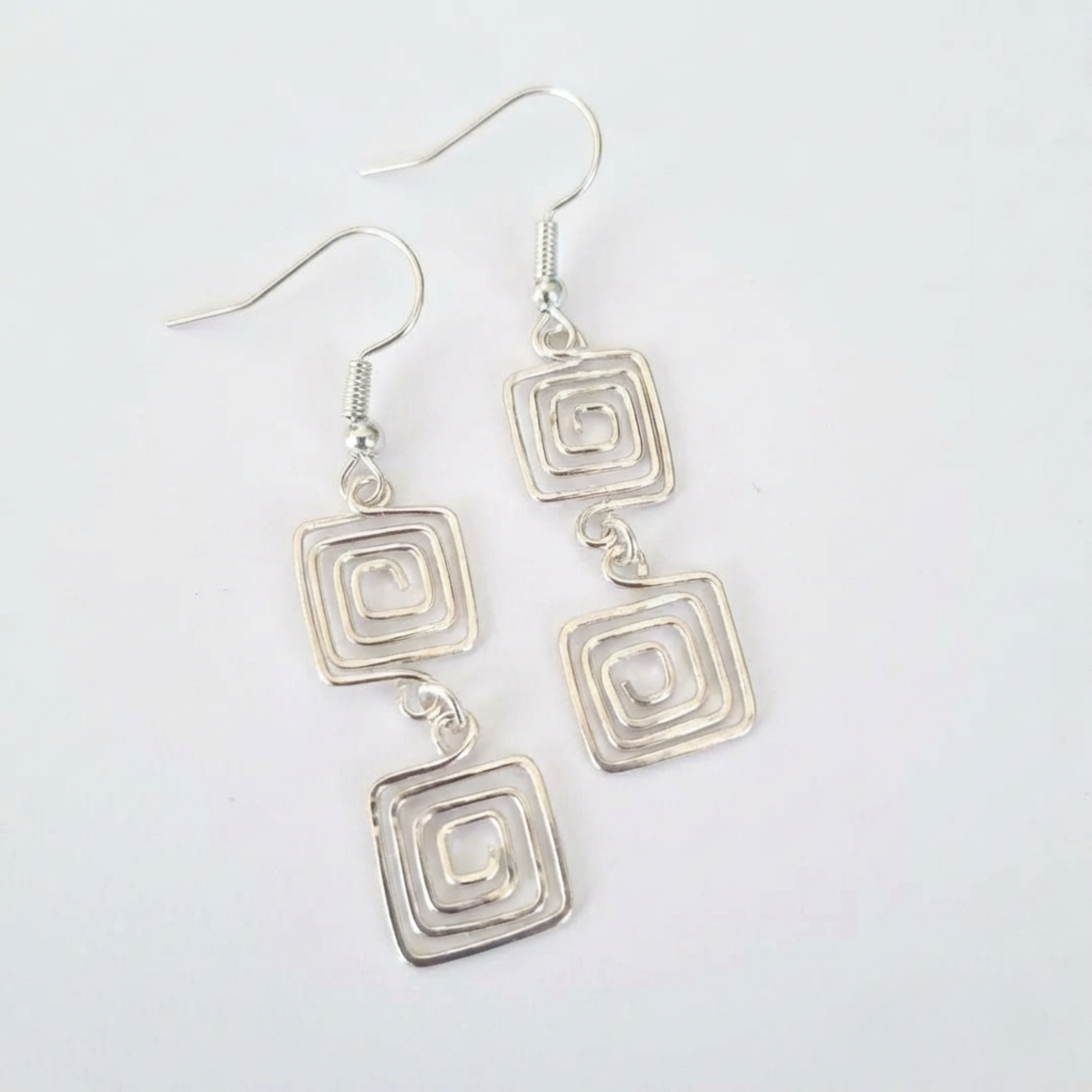 Silver square earrings on a light white background