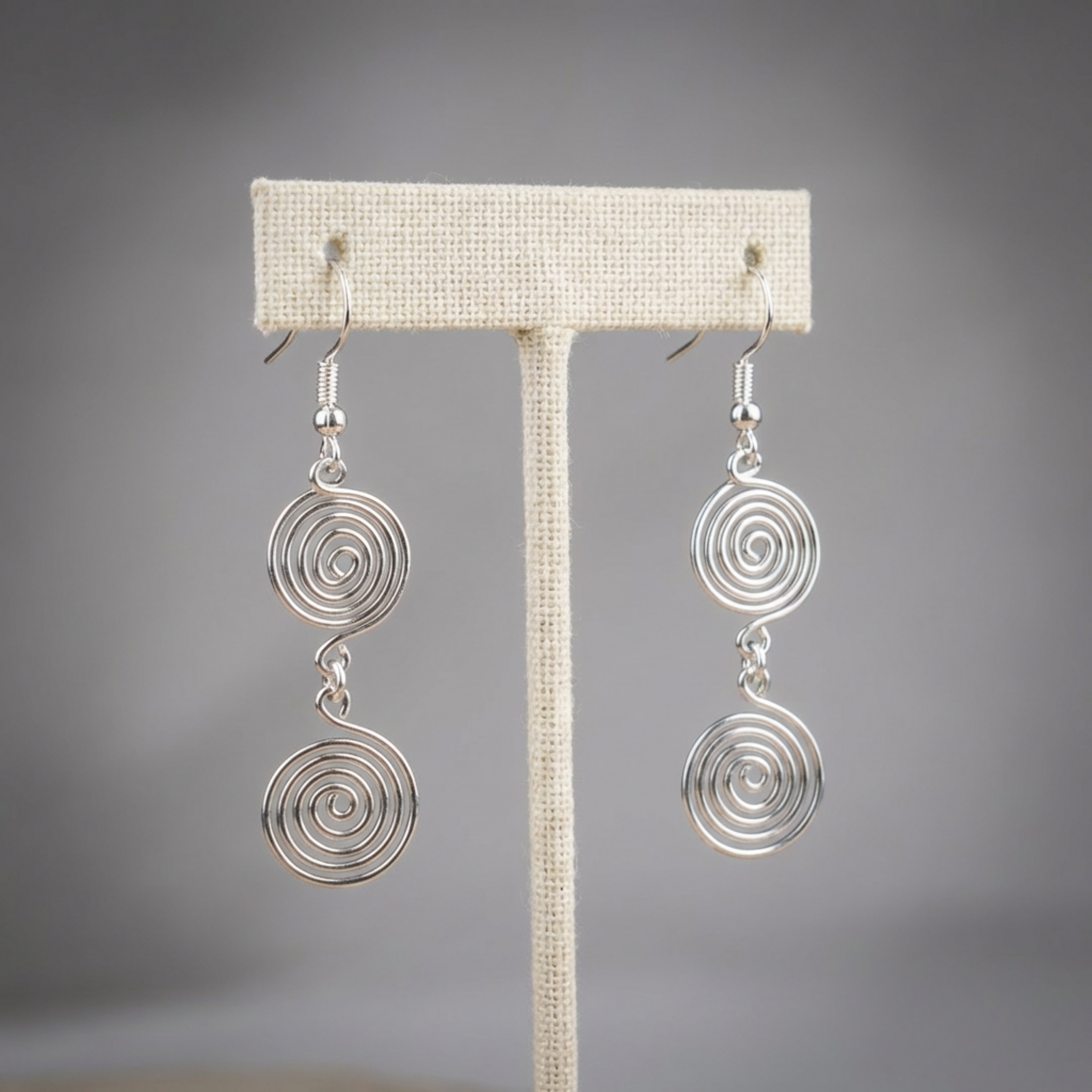 Silver spiral earrings on a grey background