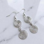 Silver spiral earrings on a marble background