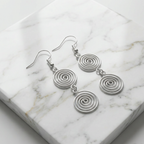 Silver spiral earrings on a marble surface