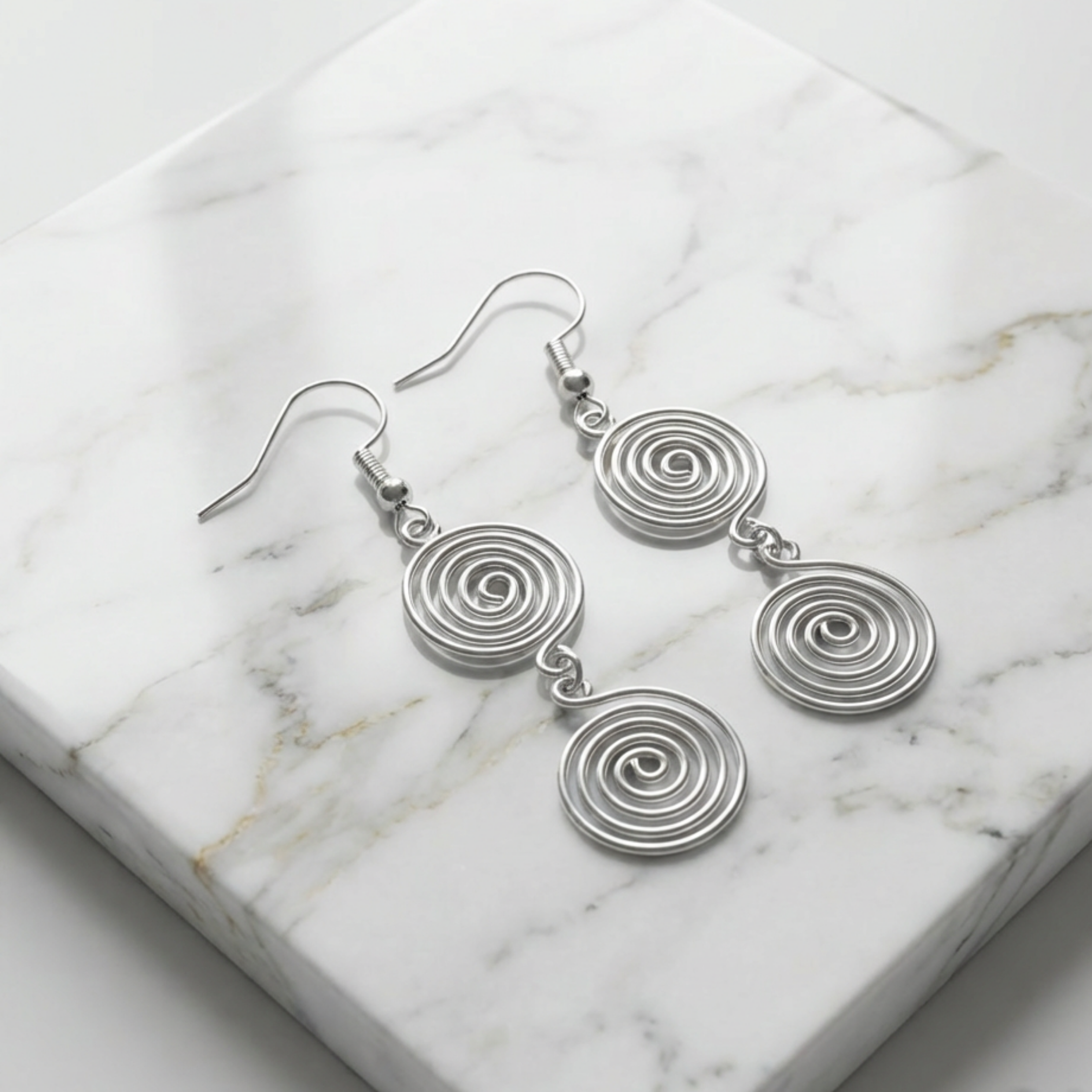 Silver spiral earrings on a marble surface