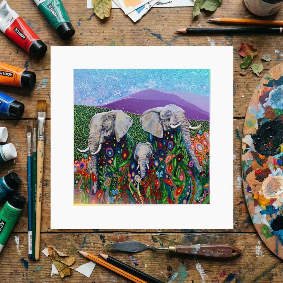 Colourful painting of elephants on a wooden surface with art supplies