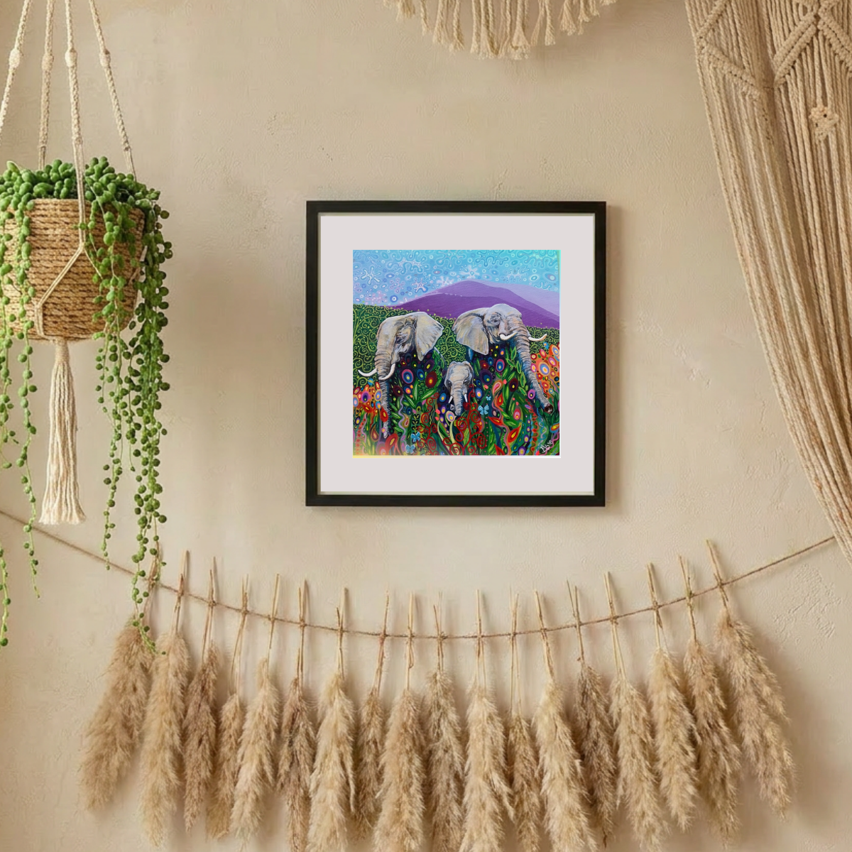 Framed artwork of elephants in a colourful landscape on a wall with decorative elements.