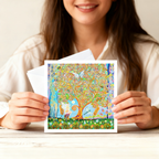 Person holding a colourful greeting card with a tree and fairy design.