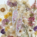 Transparent floral earrings on a bed of pressed flowers