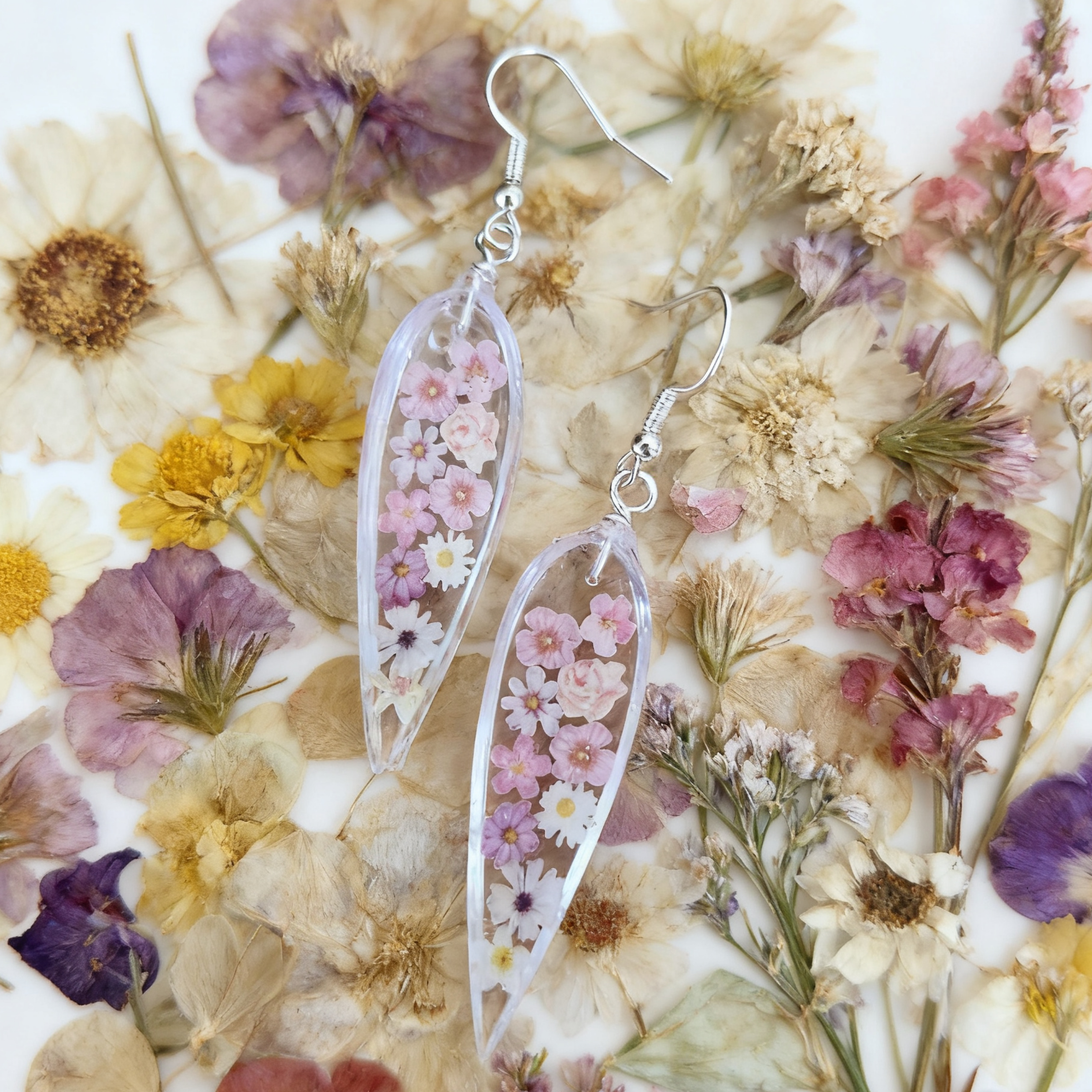 Transparent floral earrings on a bed of pressed flowers