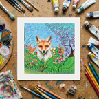 Colourful painting of a fox surrounded by flowers on a wooden surface with art supplies.