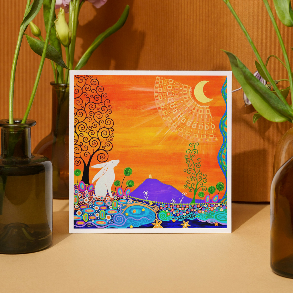 Colourful abstract artwork with a hare and landscape, framed and displayed on a surface with plants.