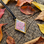 Floral pendant in a gold diamond bezel on a wooden surface
