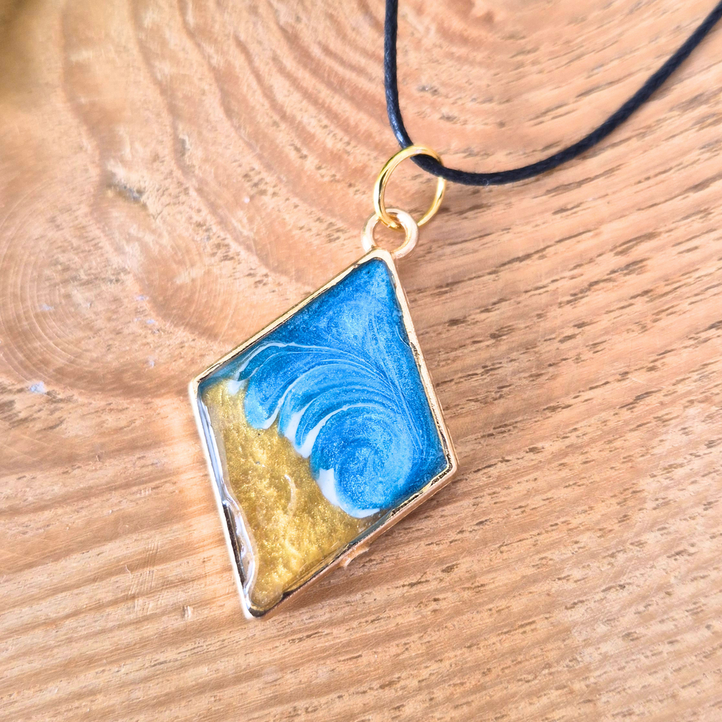 Striking wave pendant in a gold diamond bezel on a wooden surface