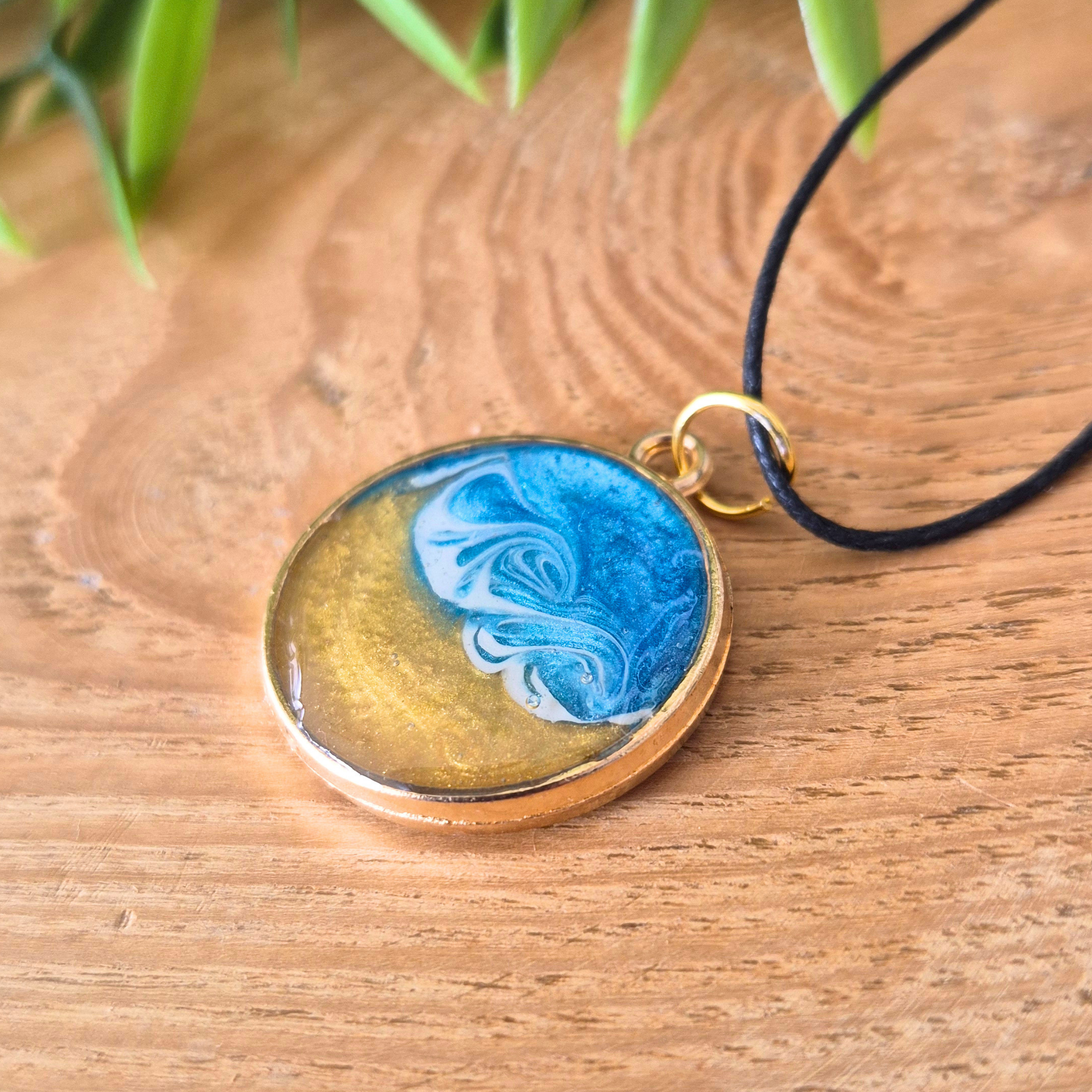 Round pendant with blue and gold design on a wooden surface