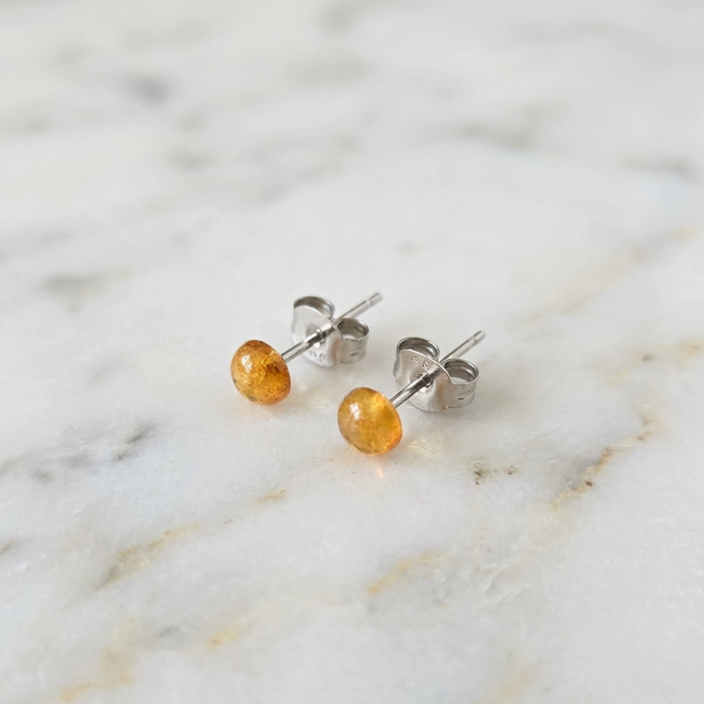 Pair of gold stud earrings on a marble surface