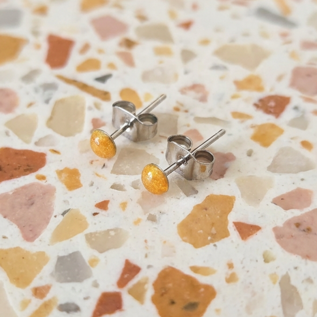 Pair of earrings with orange stones on a terrazzo-patterned surface