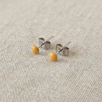 Pair of small earrings with yellow beads on a textured beige background