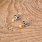 Pair of silver earrings with yellow stones on a wooden surface