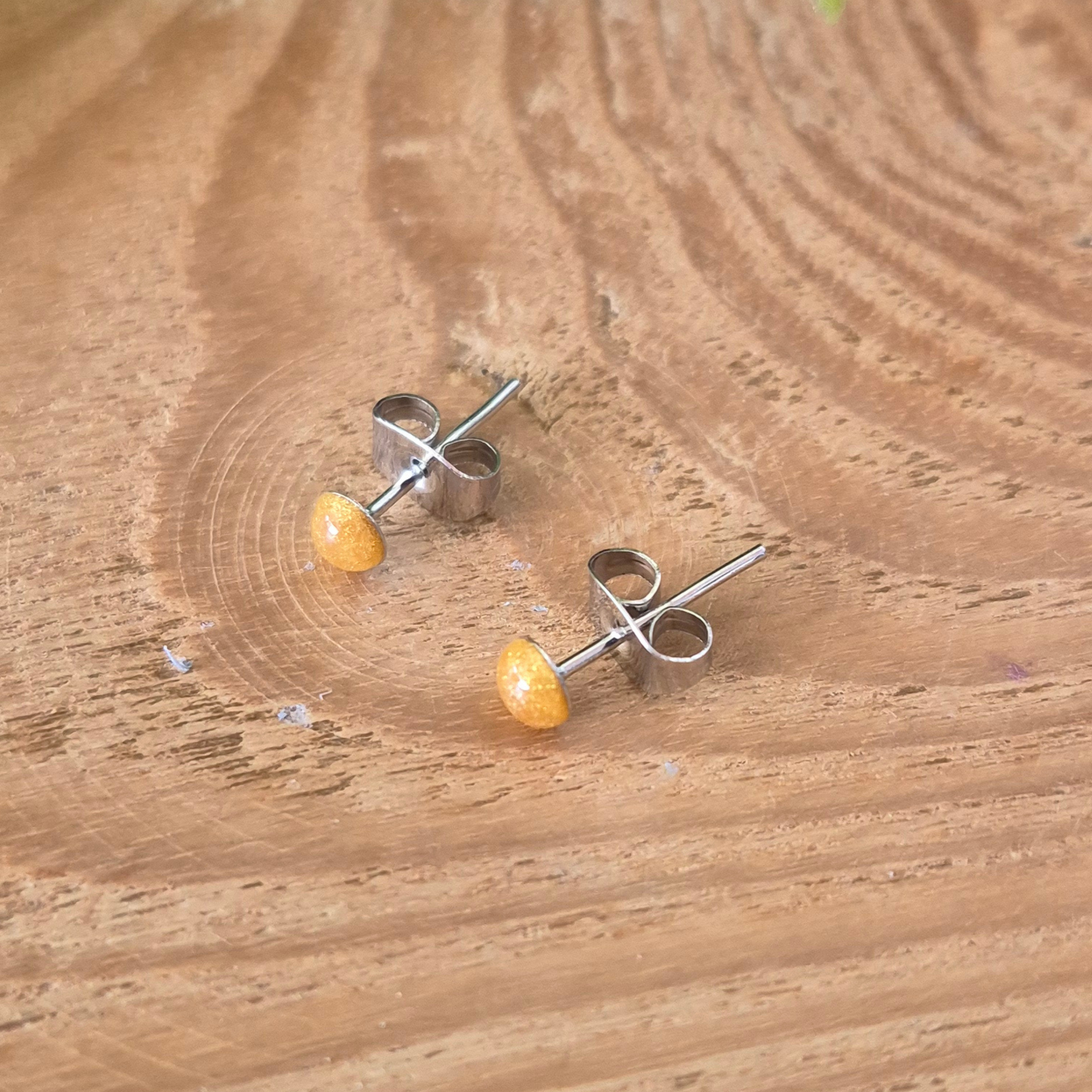 Pair of silver earrings with yellow stones on a wooden surface