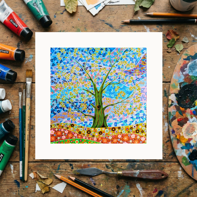 Colourful abstract painting of a tree on a wooden surface with art supplies.