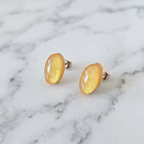 Gold oval earrings on a marble surface