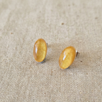 Gold oval earrings on a beige fabric background